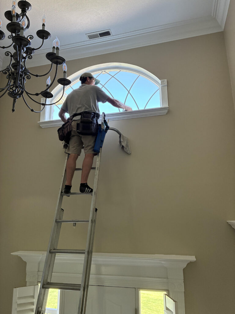 Person painting high wall window