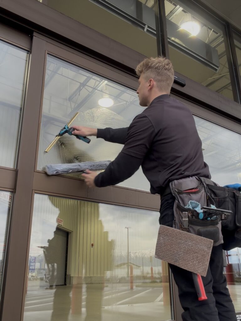 Person cleaning a large glass window.