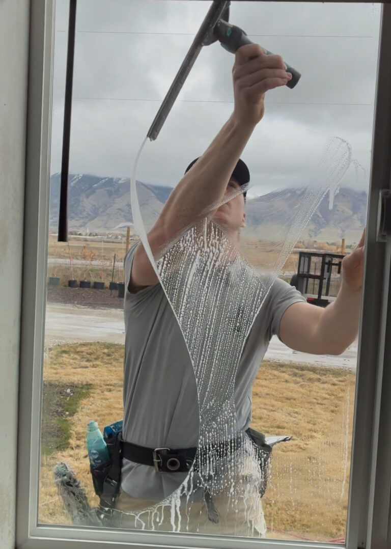 Person cleaning a window outdoors.