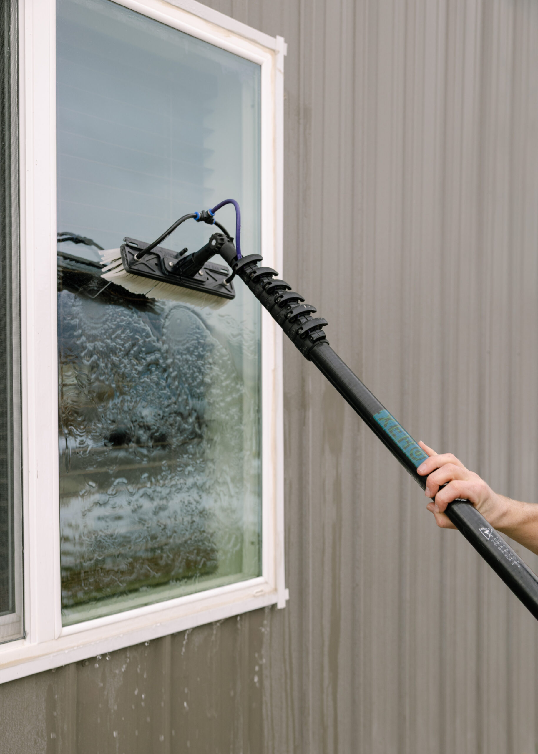 Person cleaning window with pole