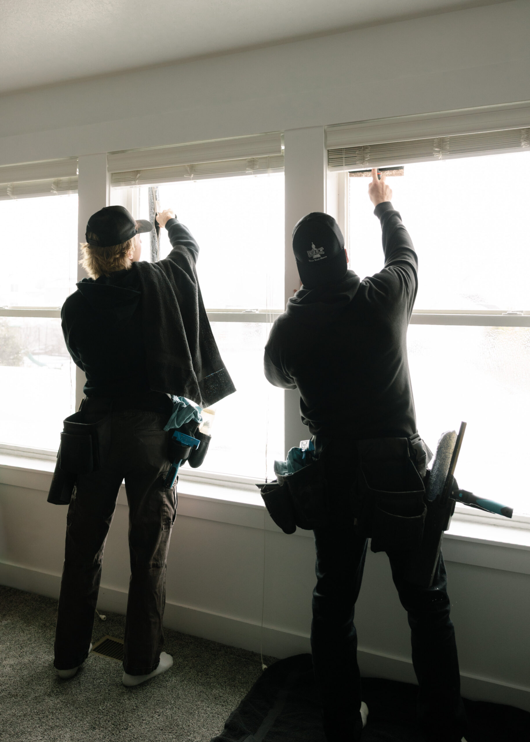 Two workers installing window blinds