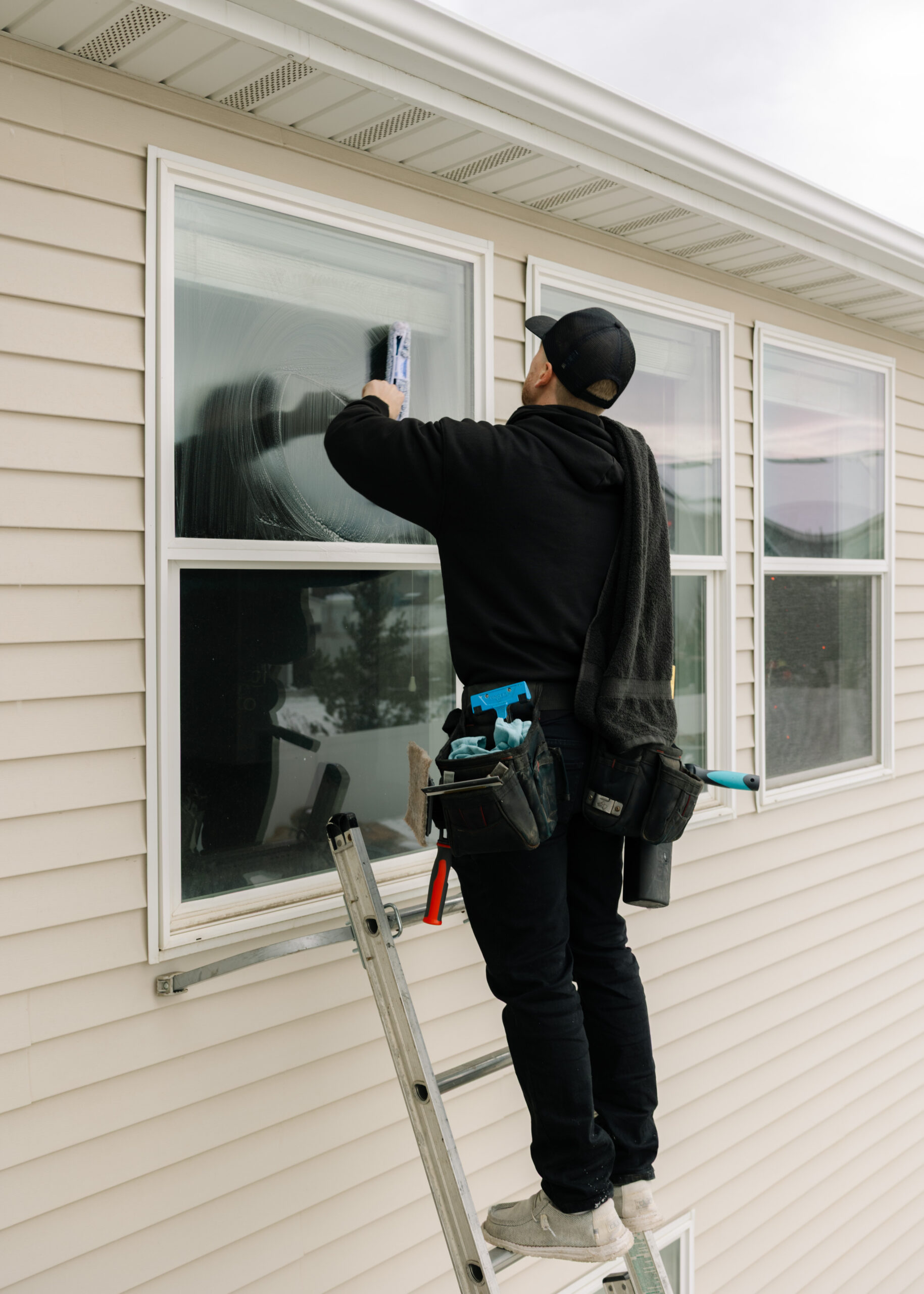 Person cleaning window on ladder