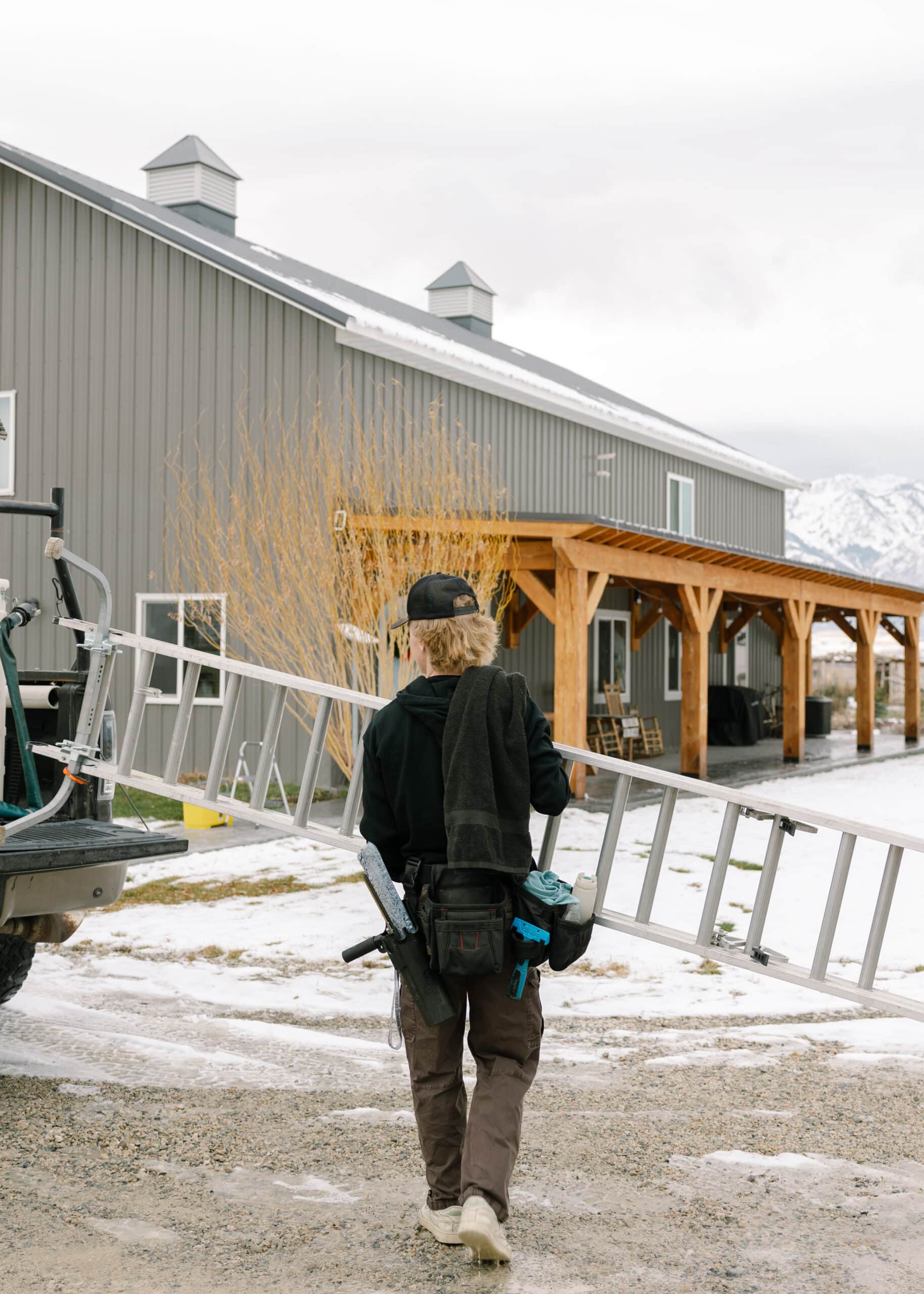 Person carrying ladder near building for window cleaning job