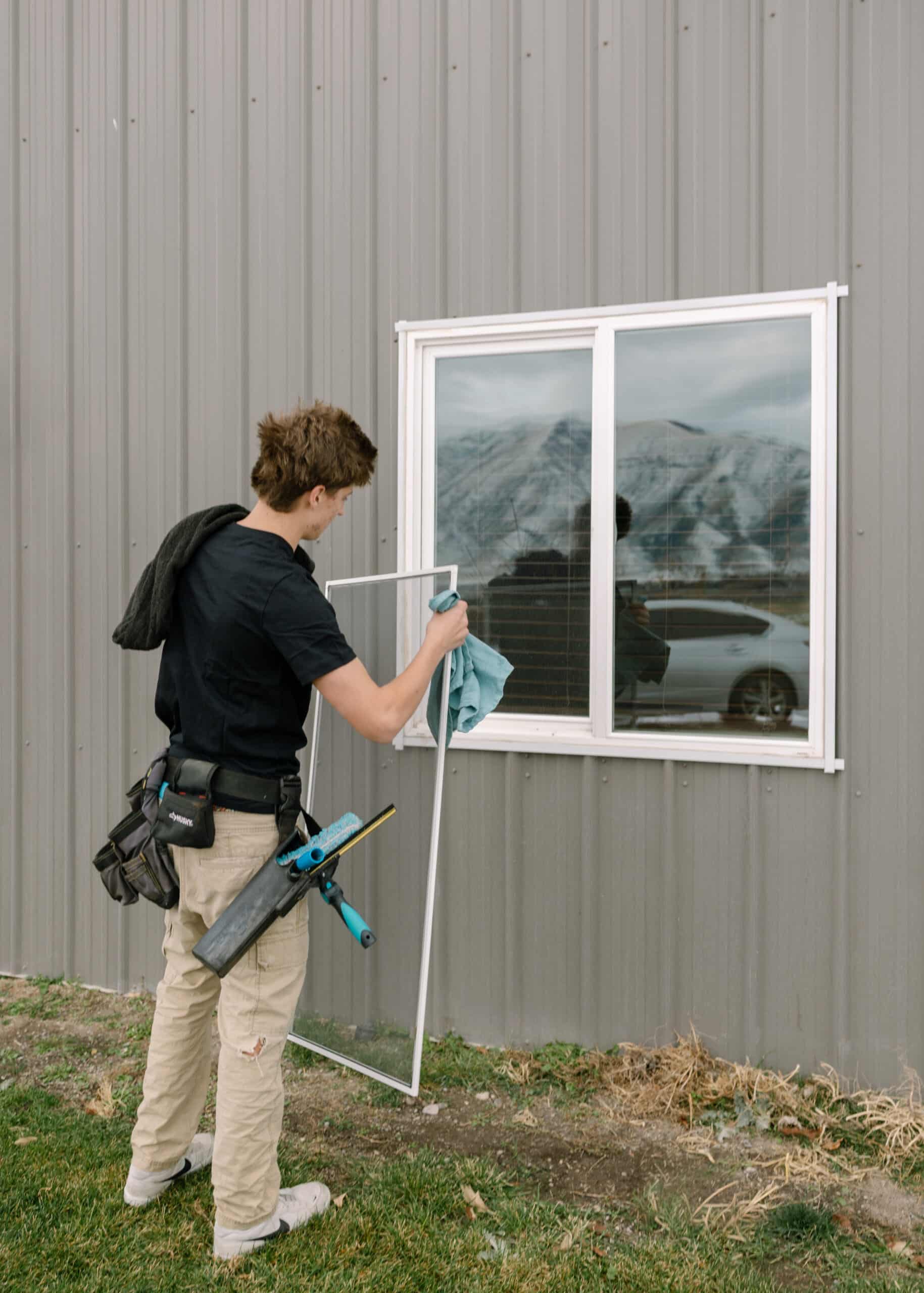Person cleaning window screen with professional tools.